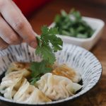 A Person Putting Cilantro on the Dumplings