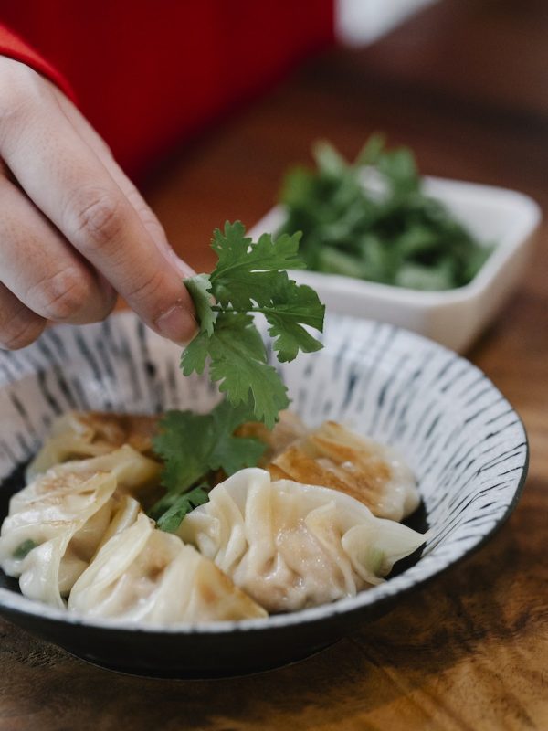 A Person Putting Cilantro on the Dumplings