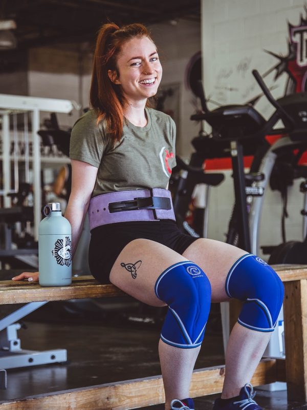woman sitting on brown wooden bench at the gym