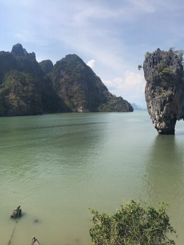 green body of water near brown rock formation during daytime